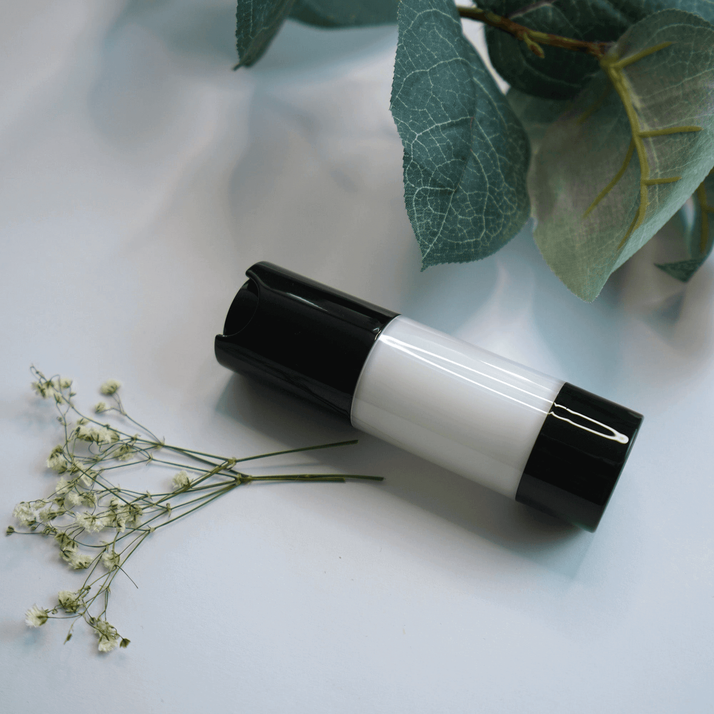 MIANIMED premium skincare bottle with black and white packaging, surrounded by delicate flowers and green leaves.