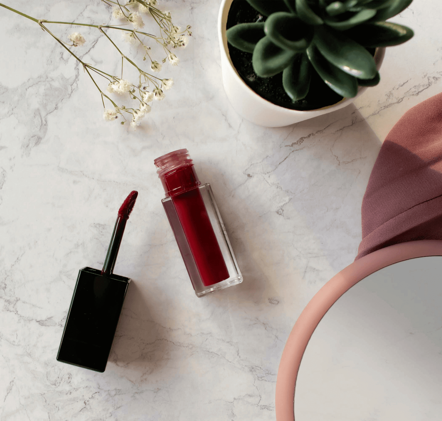 "Premium MIANIMED red liquid lipstick with succulent plant and mirror on marble surface - skincare essentials display"