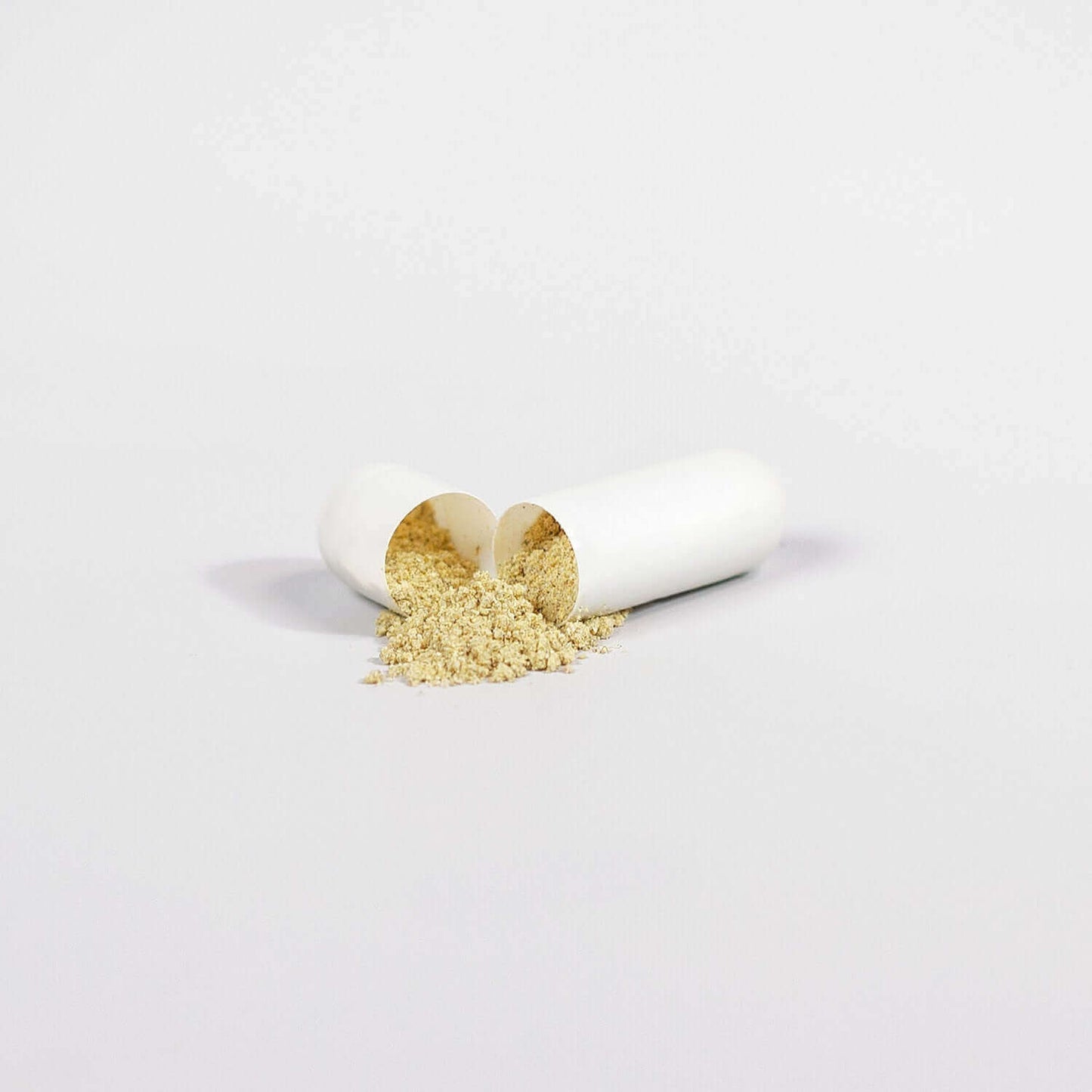 Open white capsule with spilled yellow powder on neutral background, representing MIANIMED premium skincare product.