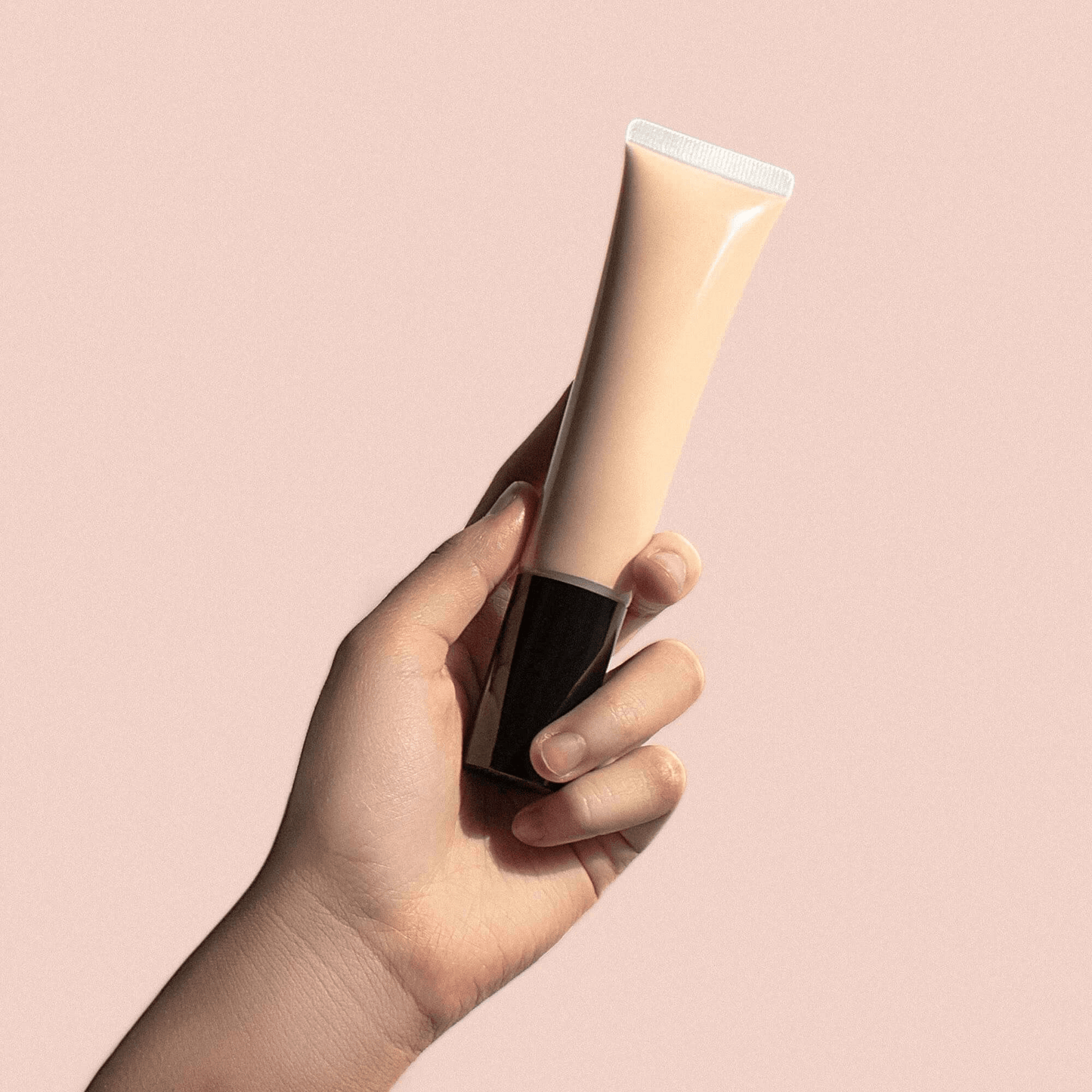 Hand holding MIANIMED Premium skincare cream in a beige tube against a pink background