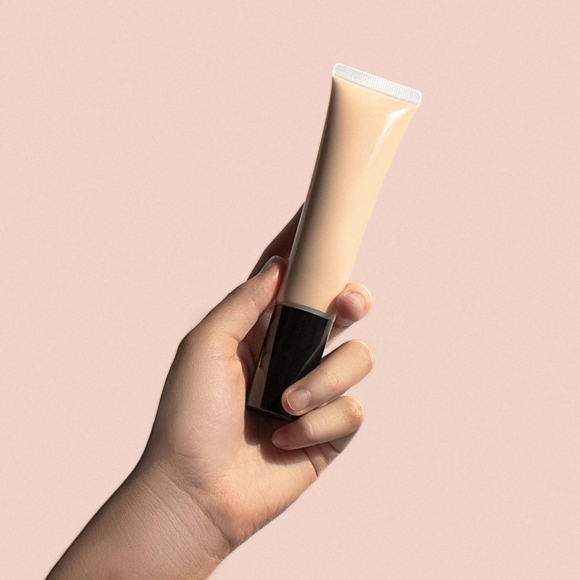 Hand holding MIANIMED premium skincare tube against plain background.