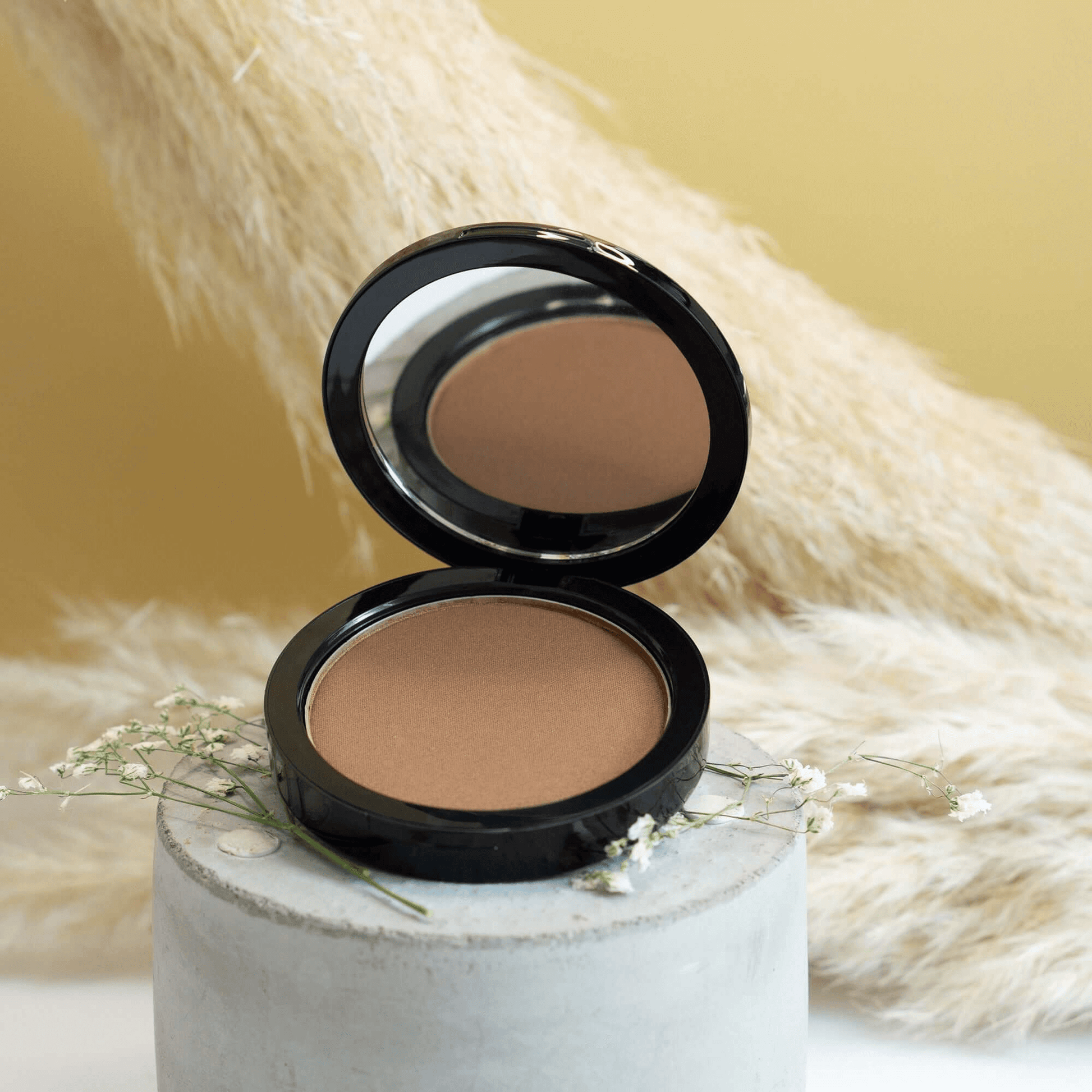 MIANIMED premium skincare product - compact powder in black casing placed on a decorative concrete base.