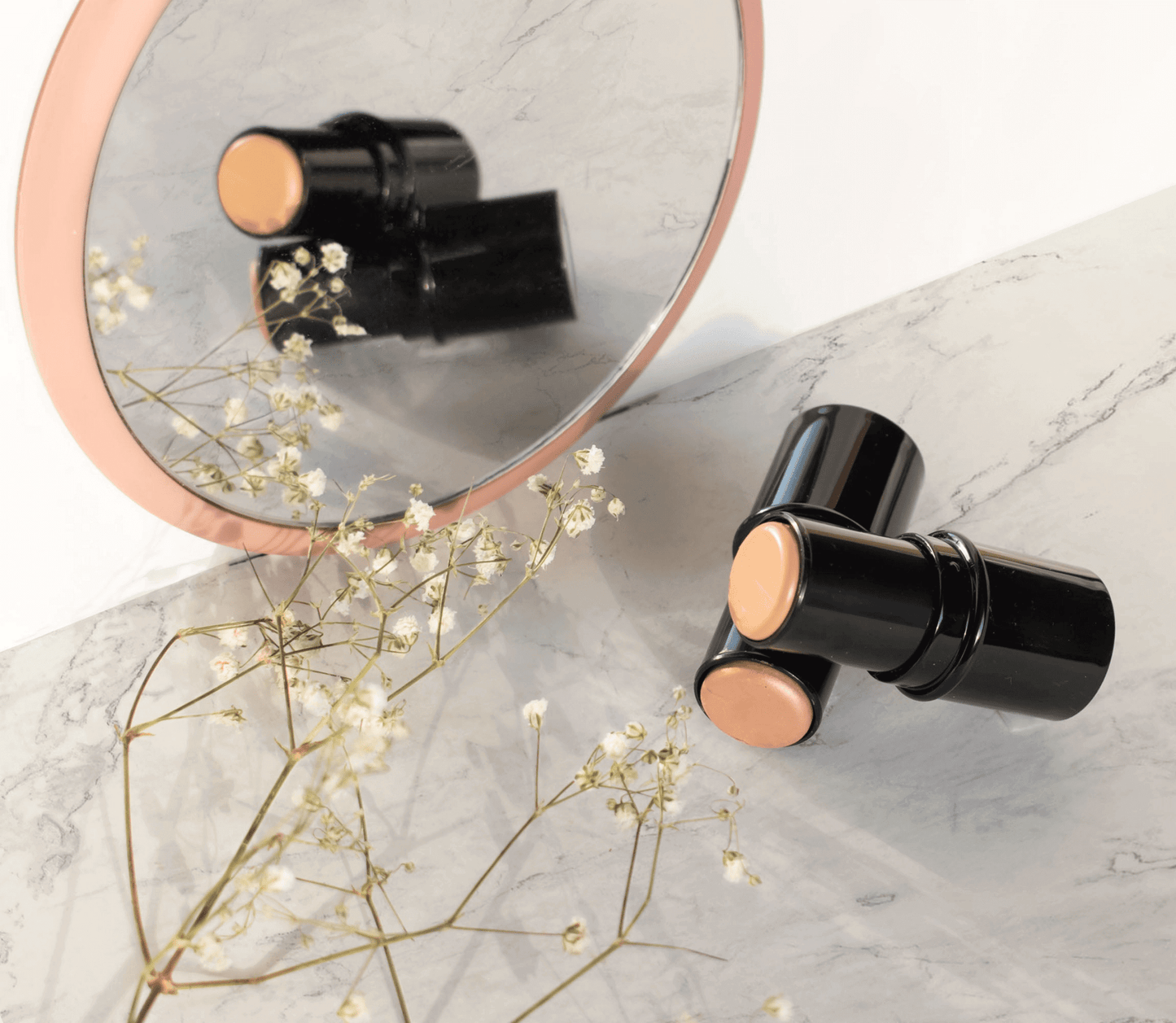 Premium MIANIMED skincare sticks displayed with a mirror and flowers on marble surface.