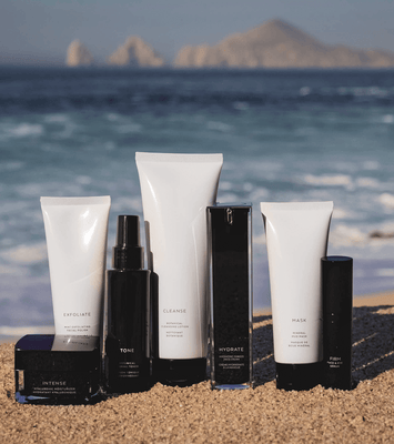 MIANIMED premium skincare products displayed on sandy beach with ocean and mountains in the background