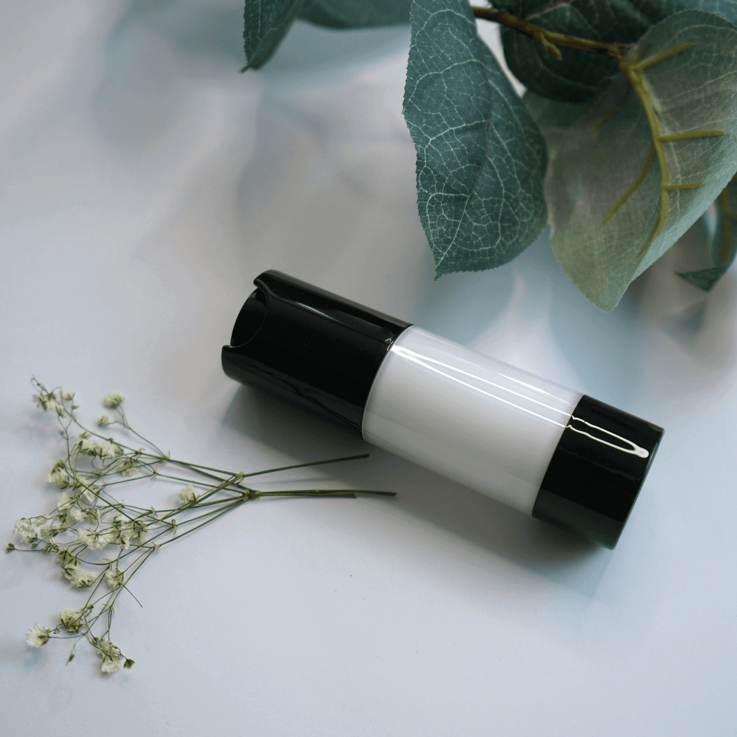 MIANIMED Premium Skincare Bottle with Green Leaves and White Flowers on a White Surface